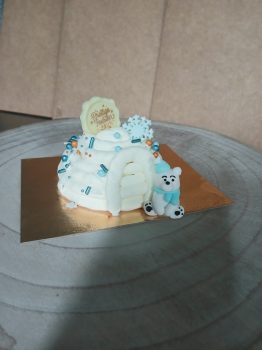 Witte ijstaart met blauwe decoraties en polar beer figuur op grijze plaat, artisanaal hoeve ijs van Limar boerderij