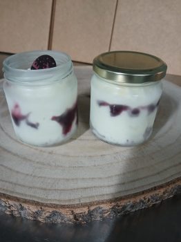 Twee glazen potten artisanaal hoeve-ijs met paarse vruchten op houten plank, gemaakt van verse melk van boerderij Limar