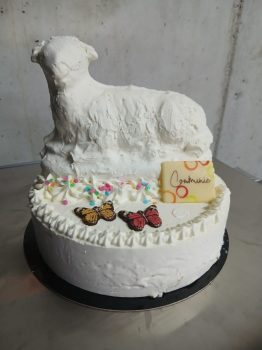 Witte ronde ijstaart met schaap sculptuur, kleurrijke sprinkels, vlinders decoratie en gele kaart op zwarte standaard